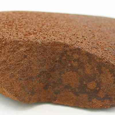 Profile of a basalt hammerstone: The image depicts a weathered, brown hammerstone with a roughly textured surface, commonly used as a tool by humans for striking and shaping materials