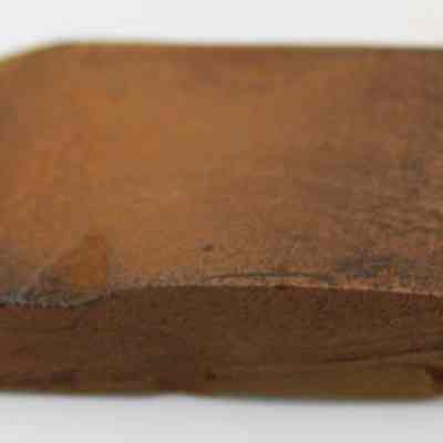 Profile of basalt adze (ko'i): The image shows a weathered, ancient adze (ko'i) head, characterized by its rectangular shape and rough, earthy surface, suggesting historical use.