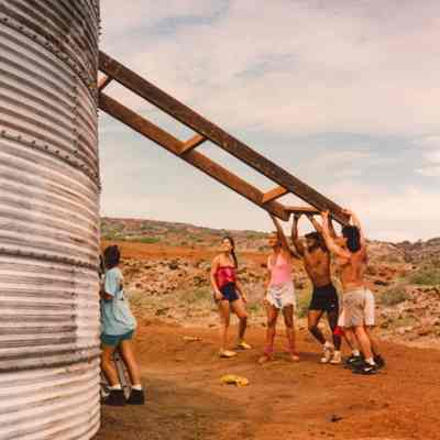 People lifting a wooden frame or ladder to the top of a water catchment