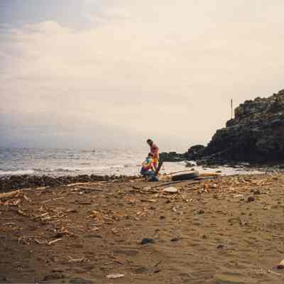 Two men uncoiling irrigation line on beach