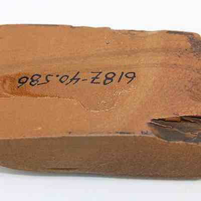 Bottom of small basalt adze (ko'i) with alternate id number visible: The image shows an ancient stone adze (ko'i) head with a rough, rectangular shape. Its surface has an inscription, for identification and cataloging purposes.
