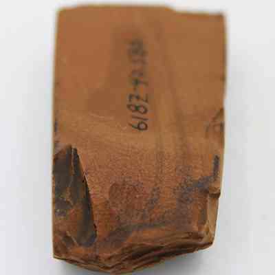 Lenthwise view of basalt adze (ko'i): The image shows a stone adze (ko'i) head with a rectangular shape, featuring a rough, chipped surface and a number inscribed on it.