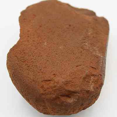 Closeup of a hammerstone: The image depicts a reddish-brown hammerstone with a rough, textured surface, likely used by humans for toolmaking or processing materials.