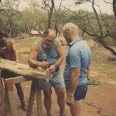 Three unidentified men working on log