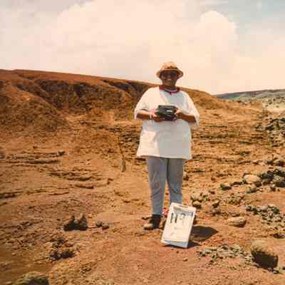 An unidentified woman holding a camera in hardpan area