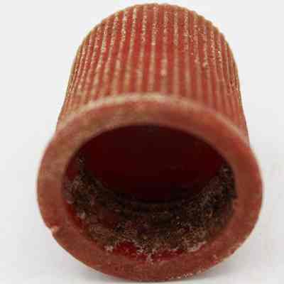 Inside plastic cap: The image depicts a close-up of a cylindrical, textured, red object with visible dirt and grime on its interior surface, possibly indicating wear or use.
