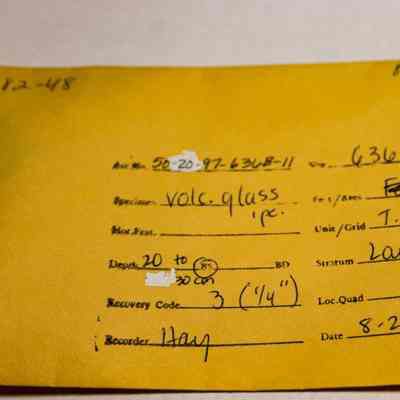 Artifact envelope for a piece of volcanic glass: The image shows a yellow envelope detailing archaeological specimen information, including accession number, stratum, and date, with handwritten notes.