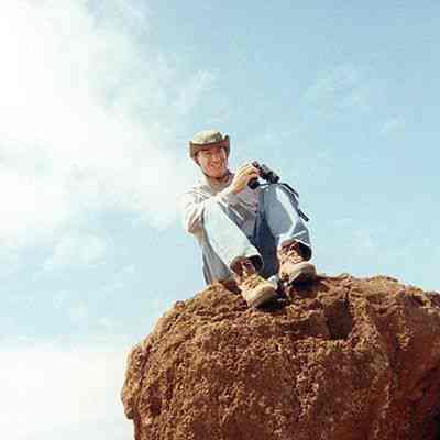 Unidentified man sitting on a pohaku (boulder)