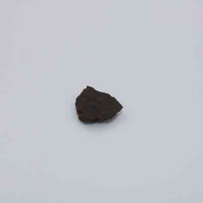 Basaltic glass flake: A small basaltic glass flake rests centrally on a plain white background.