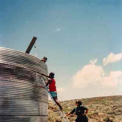 Three people working on a water catchment structure