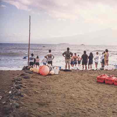 Group of people watching cargo being swum in via tow line