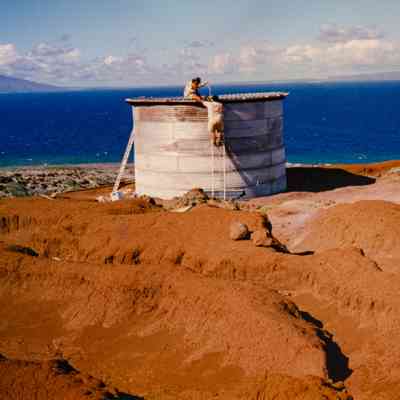 Two people working on top of water tank