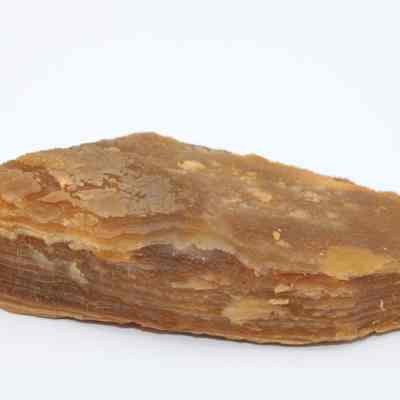 Closeup profile of agate flake: The image shows a brown agate flake with layered texture, smooth surface, and natural earthy tones, resting against a plain white background.