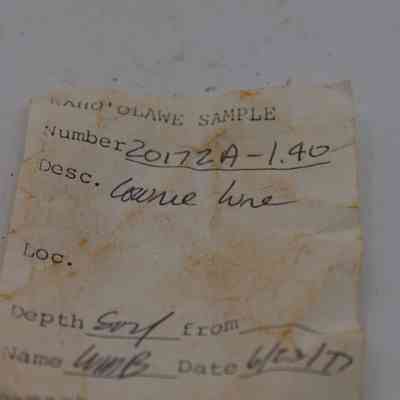 Artifact slip for cowrie shell lure: The image displays a worn and slightly stained sample label from Kaho'olawe, featuring handwritten notes detailing a sample number, description, and date.