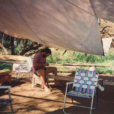Two men working under a tarp shelter