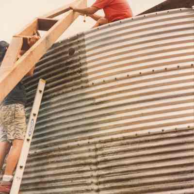 People hauling wood frame onto metal water catchment structure
