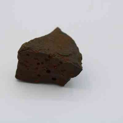 Closeup of basaltic glass core: The image shows a piece of basaltic glass core, displaying a rough texture and a dark surface with some visible pores.