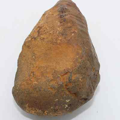 Lengthwise view of basalt hammerstone: The image shows a rough, elongated stone tool, likely a hammerstone or adze preform, with visible surface markings and a worn texture on its surface.