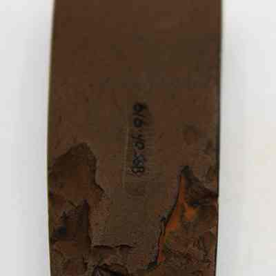 Lengthwise view of polished side of basalt adze (ko'i) with alternate id # visible: The image shows a weathered, dark brown adze (ko'i) fragment with jagged edges, displaying signs of wear and age, possibly used for woodworking.