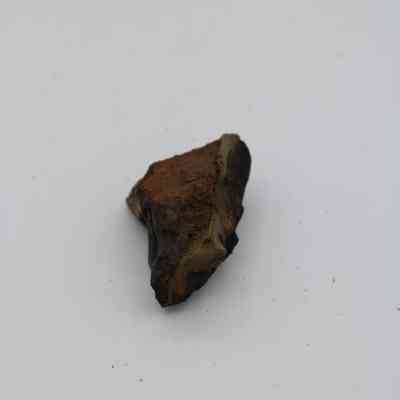 Closeup of basaltic glass core: The image shows a fragment of basaltic glass core, exhibiting rough, dark surfaces with a striking earthy texture.