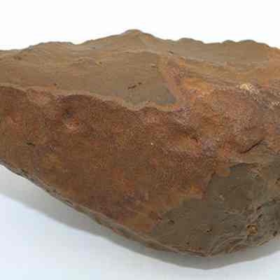 Profile of basalt hammerstone: The image shows a roughly oval stone tool, possibly a hammerstone or adze preform, with a textured, weathered brown surface.