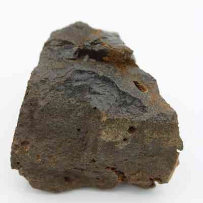 Closeup of basaltic glass core: The image shows a rough, dark basaltic glass core with a porous texture and irregular surface.