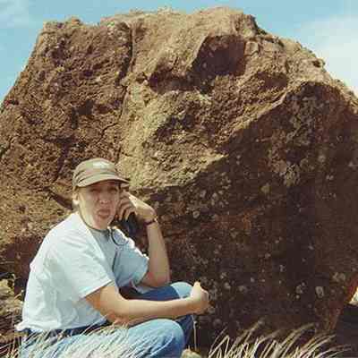 Unidentified woman sitting in front of a large pohaku (stone)