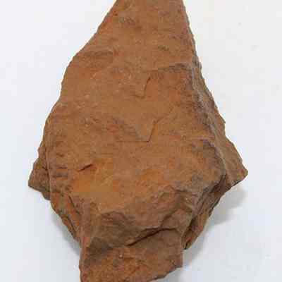 Lengthwise view of adze (ko'i) flake: The image shows a rough, brown adze (ko'i) flake with uneven surfaces, likely used for ancient woodworking, lying on a flat surface.