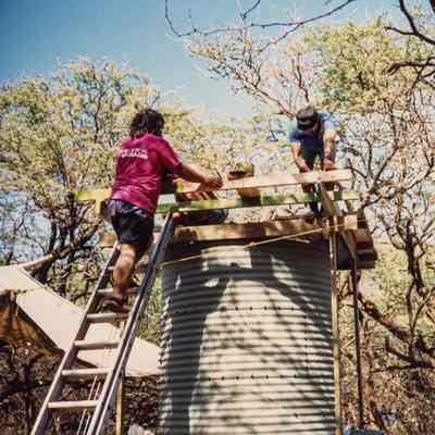 Two people working on top of water catchment structure
