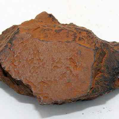 Side of adze (ko'i) flake: The image depicts a rough, brownish stone likely used as an adze (ko'i) flake, showcasing a jagged, irregular surface indicative of tool-making processes.
