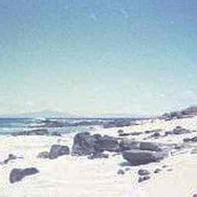 White sandy beach with black rocks