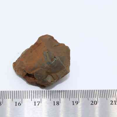 Closeup of basaltic glass core with ruler: The image shows a small basaltic glass core with a rugged surface, placed next to a ruler for scale.
