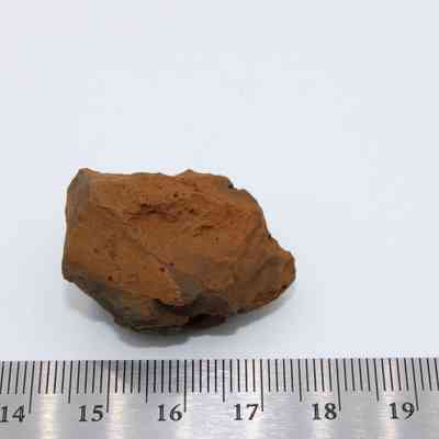 Closeup of basaltic glass core with a ruler: A piece of basaltic glass core rests on a white surface, measuring around 5 cm next to a ruler.