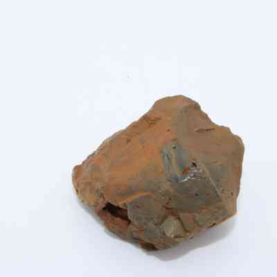 Closeup of basaltic glass core: The image shows a rough, irregularly shaped basaltic glass core with a mix of earthy brown and subtle grayish tones, pointing to its volcanic origin.