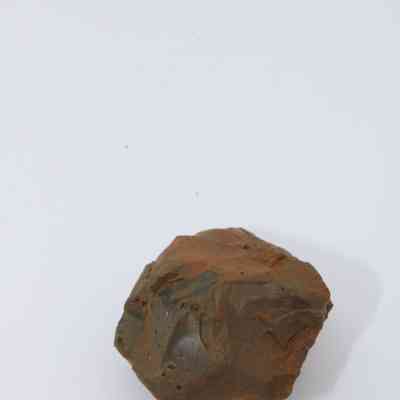 Closeup of basaltic glass core: A rough, irregularly shaped basaltic glass core with earthy tones is displayed against a white background, highlighting its natural textures.