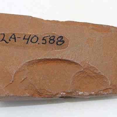 Basalt adze (ko'i) fragment with alternate id number visible: The image shows a fragment of an adze (ko'i) with a rough, textured surface and an identification number "112A-40.588" written in black ink.