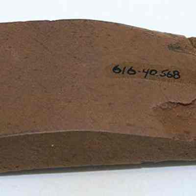 Polished side of basalt adze (ko'i) fragment: The image shows a brown adze (ko'i) fragment with surface wear and writing labeled "616-40-568" on its surface, indicating cataloging details.
