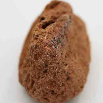 Closeup lengthwise view of a small breadloaf sinker: The image shows a close-up view of a rough, textured stone sinker, possibly used for fishing, displaying small black numbers written on one side.