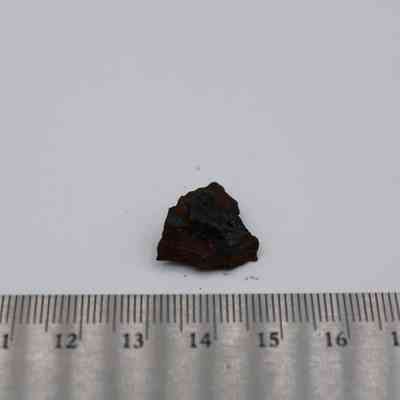 Basaltic glass core with ruler: A small basaltic glass core is placed next to a metric ruler on a white background for scale reference.