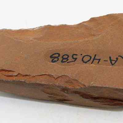 Basalt adze (ko'i) fragment with alternate id number visible: The image shows a brown, irregularly shaped adze (ko'i) fragment, marked with the code "112A-40.588," indicating an archaeological context.