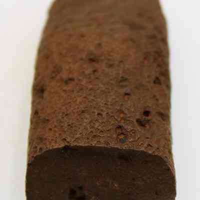 Lengthwise view of an adze preform: The object in the image appears to be a cylindrical piece of reddish-brown, porous rock.
