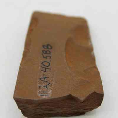 Lengthwise view of an adze (ko'i) fragment with alternate id number visible: The image shows a fragment of an adze (ko'i), with a rough brown surface and clear markings as "12A-40.588," displayed against a plain background.
