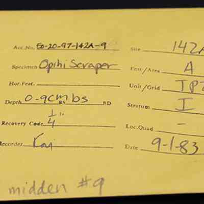 Artifact envelope for 'opihi scraper: The image shows a yellow artifact envelope detailing an archaeological find, including specimen "Opihi Scraper," from site "142A," and date "9-1-83."