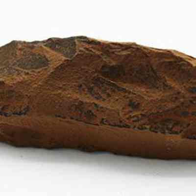 Side view of quadrangular adze: The image displays a stone tool, possibly an adze, with a rough, brown surface and visible flake scars.
