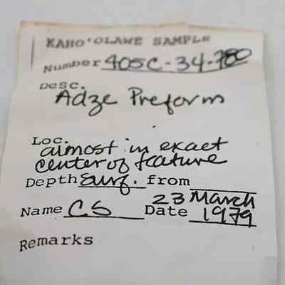 Artifact slip for adze preform: The image shows a handwritten label for a sample from Kaho'olawe, describing an "Adze Preform" found near a center of a feature.