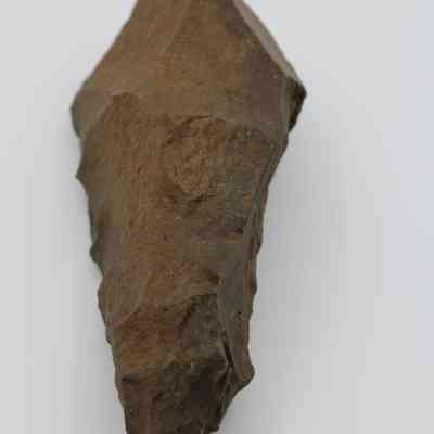 Lengthwise of adze blank: The image shows an adze blank, which is a roughly shaped, stone tool precursor, likely used in ancient times for woodworking purposes.