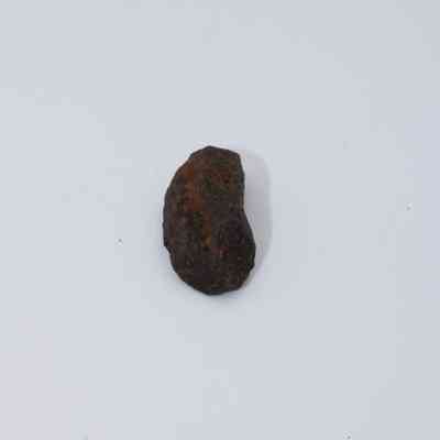 Closeup of basaltic glass core: The image displays a dark, irregularly shaped basaltic glass core resting on a plain white surface.