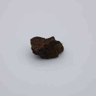 Closeup of basaltic glass core: The image shows a small, dark-colored basaltic glass core, set against a plain background.