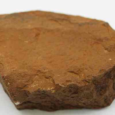 Grinding stone: The image shows a rough, brown stone with an uneven surface, likely used as a grinding tool.