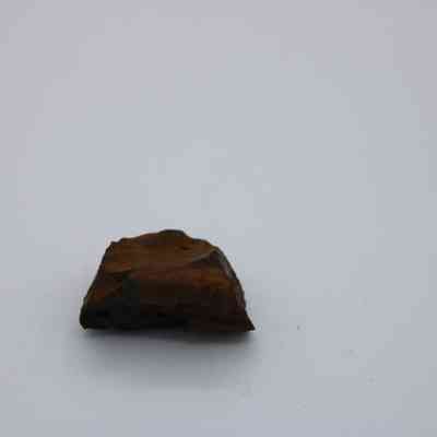 Closeup of basaltic glass core: The image shows a singular piece of basaltic glass core resting on a plain surface.